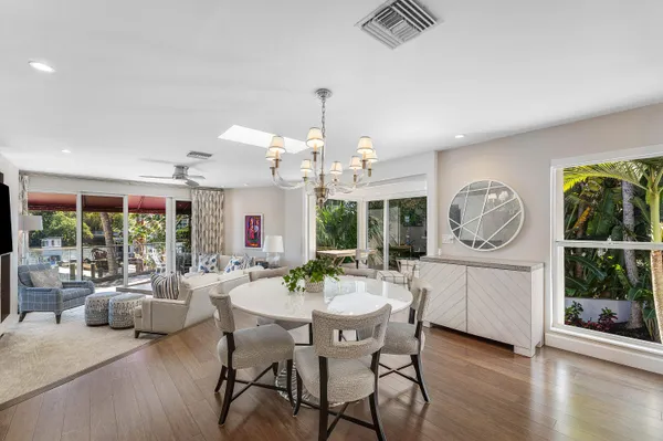a dining room with wooden floor a chandelier a wooden table and chairs