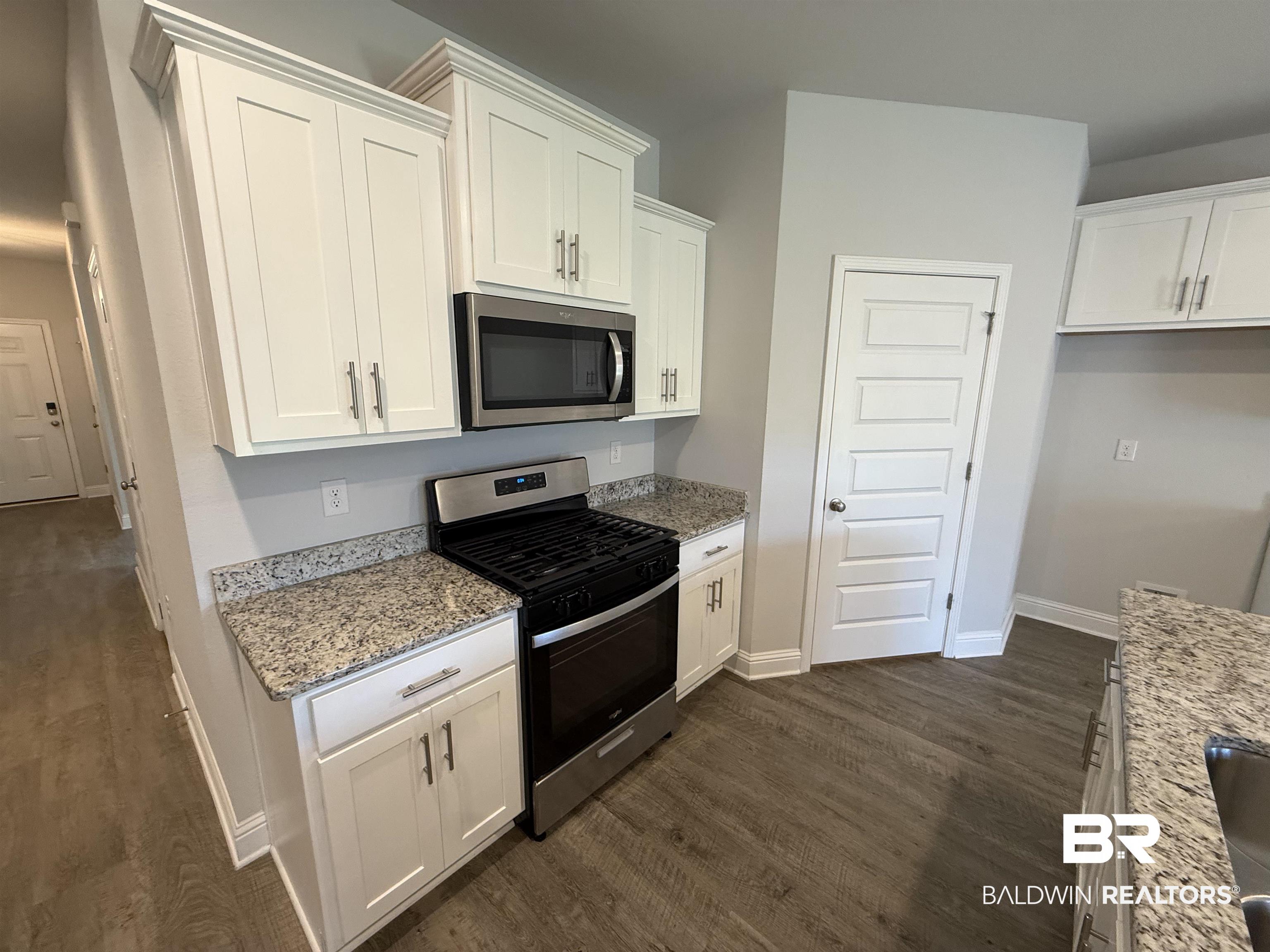 23247 Lieutenant Avenue Foley, AL 36535 - Photo 18 of 47 Kitchen featuring granite countertops, white cabinetry, stainless steel appliances, wood-finish flooring, and a paneled door