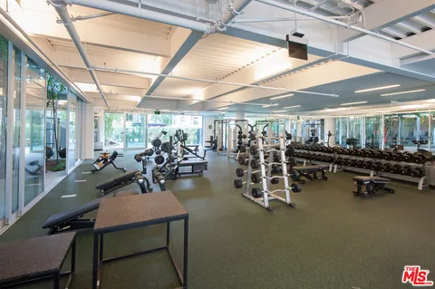 a room with gym equipment and large windows