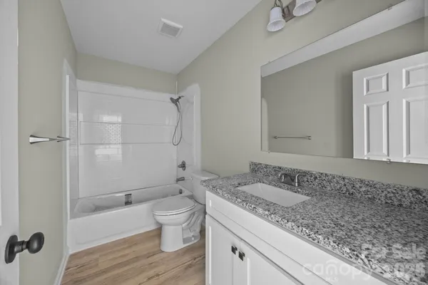 a bathroom with a granite countertop sink a toilet and shower