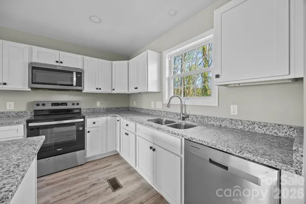 a kitchen with stainless steel appliances granite countertop a sink a stove a microwave and wooden cabinets