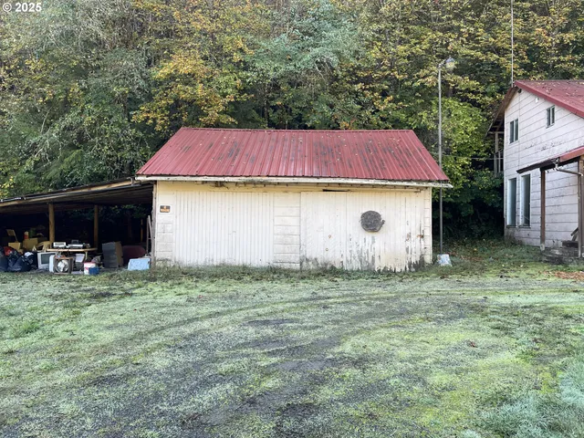 a view of a yard in front of a house with table and chairs under an umbrella