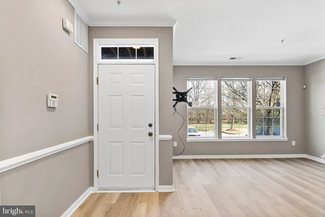 a view of an empty room with a window and wooden floor