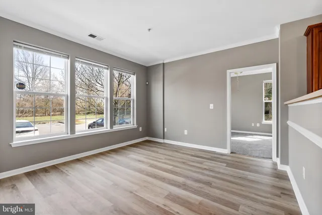 a view of an empty room with a window and wooden floor