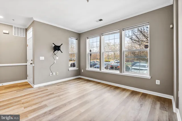 a view of an empty room with a window and wooden floor