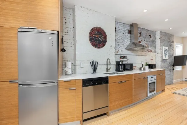 a kitchen with stainless steel appliances granite countertop a refrigerator a oven a sink and dishwasher with wooden floor