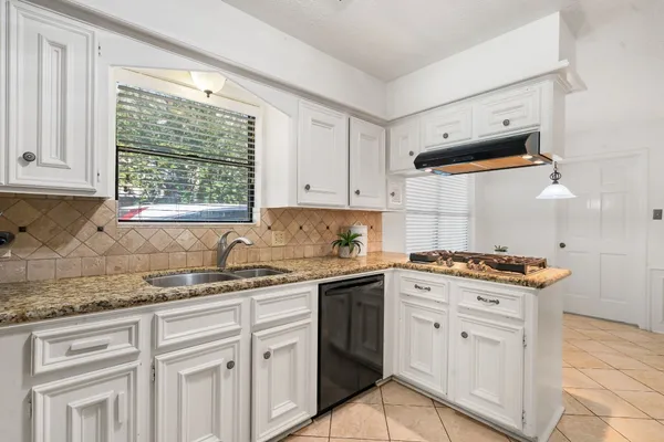 a kitchen with granite countertop white cabinets and a window
