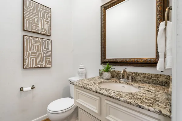 a bathroom with a granite countertop toilet sink and mirror