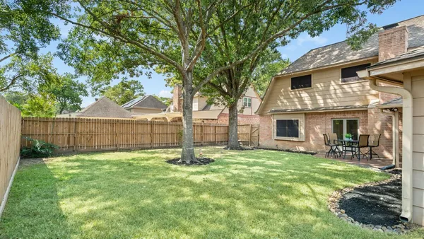 a view of backyard with table and chairs and wooden fence
