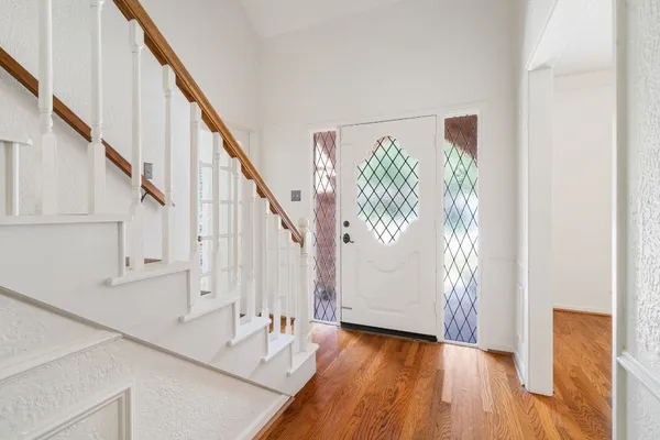 a view of front door with stairs and wooden floor