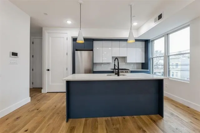 a kitchen with stainless steel appliances granite countertop a sink a refrigerator and wooden floors