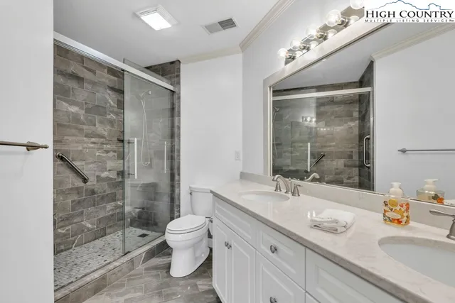 a bathroom with a granite countertop sink a toilet a mirror and shower
