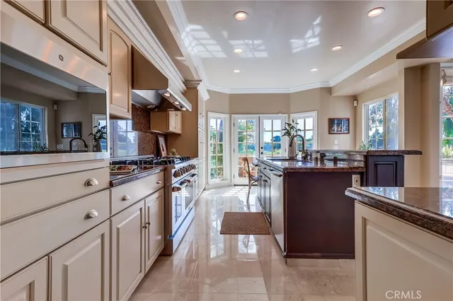 a kitchen with stainless steel appliances kitchen island granite countertop a refrigerator a stove and a sink with large countertops