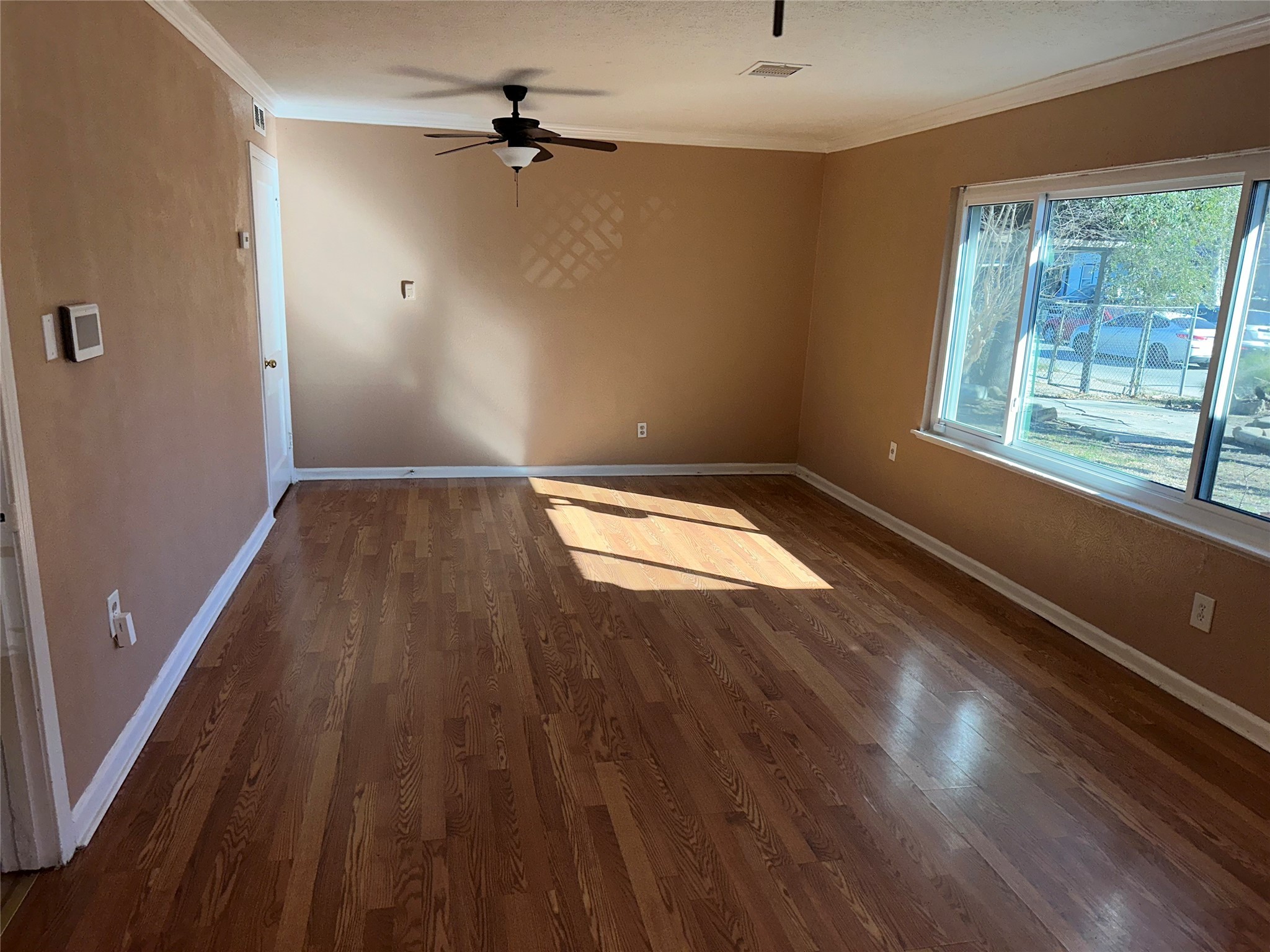 5715 Beldart Street Houston, TX 77033 - Photo 3 of 12 an empty room with wooden floor and windows