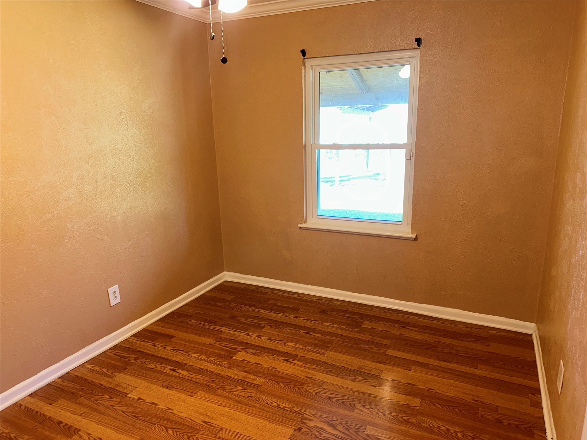 5715 Beldart Street Houston, TX 77033 - Photo 10 of 12 a view of an empty room with wooden floor and a window
