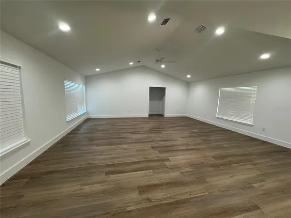 an empty room with wooden floor and windows