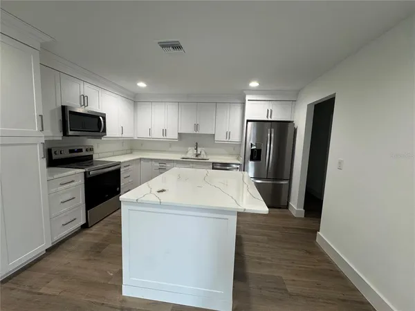 a kitchen with a sink a refrigerator a microwave and cabinets