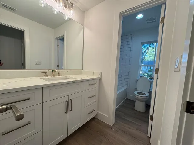 a bathroom with a granite countertop toilet sink and mirror