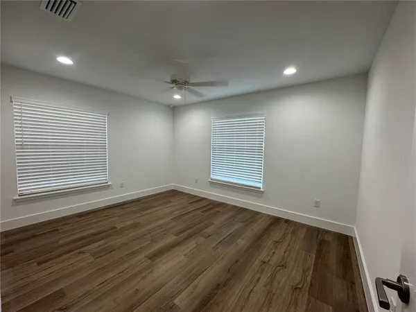 an empty room with wooden floor and windows
