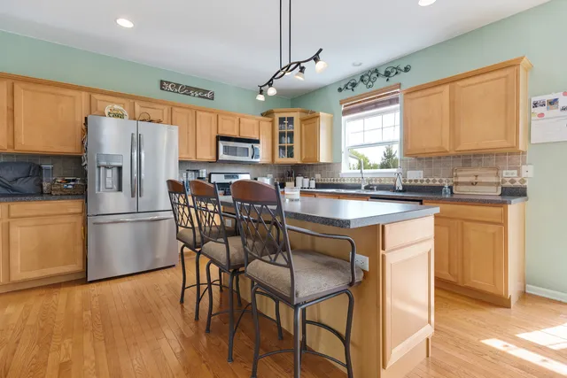 a kitchen with stainless steel appliances granite countertop a stove a refrigerator a sink a stove and white cabinets with wooden floor