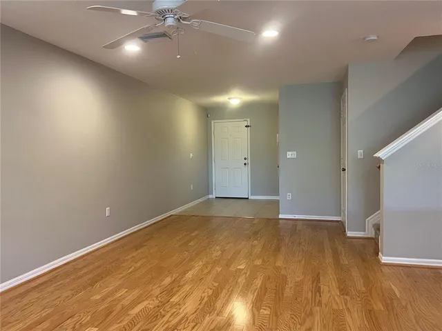 an empty room with wooden floor and ceiling fan