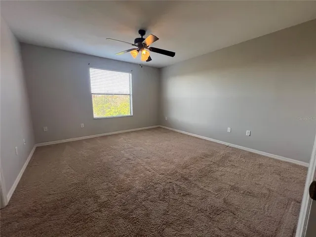 an empty room with windows and chandelier fan