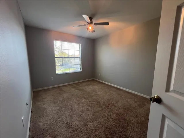 an empty room with a window and a fan