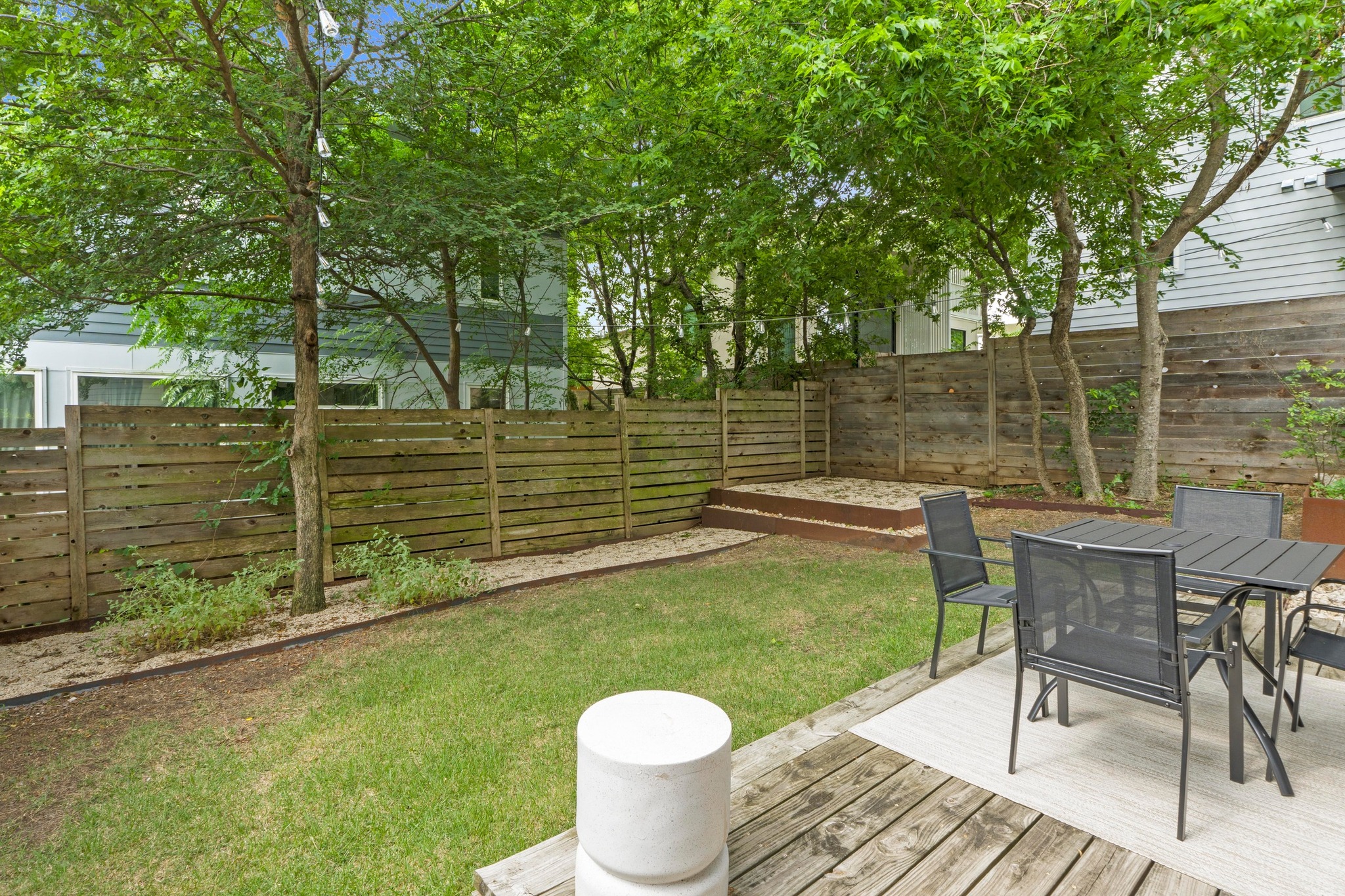 1706 Perez Street, Unit 2 Austin, TX 78721 - Photo 26 of 29 A verdant yard offers a delightful outdoor dining space on a wooden deck, perfect for leisure.