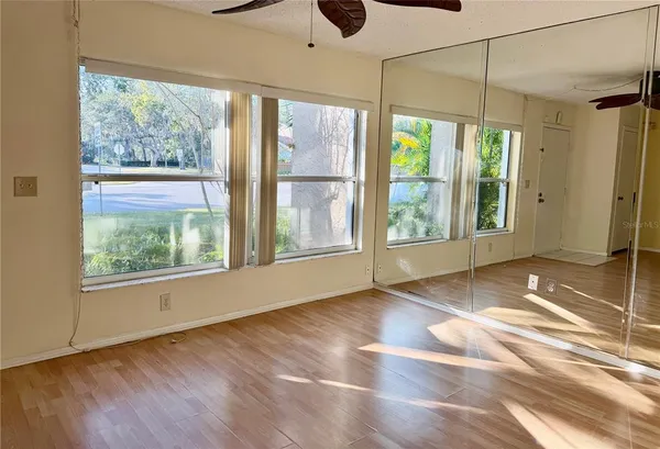 a view of an empty room with wooden floor and windows