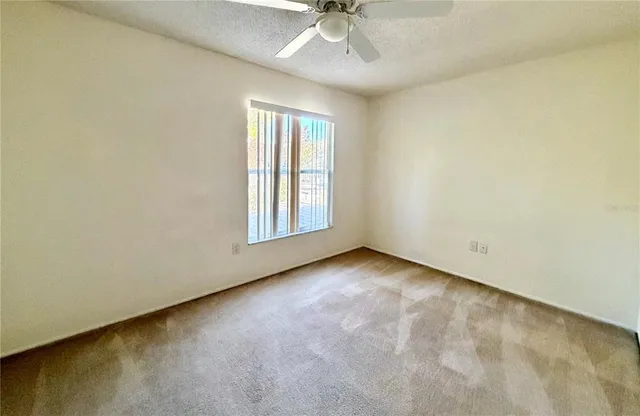 an empty room with a window and a ceiling fan