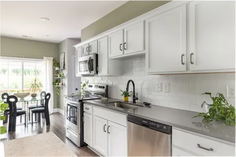a kitchen with granite countertop a stove a sink a window and white cabinets