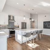 a kitchen with stainless steel appliances granite countertop a stove top oven a sink a refrigerator and chairs