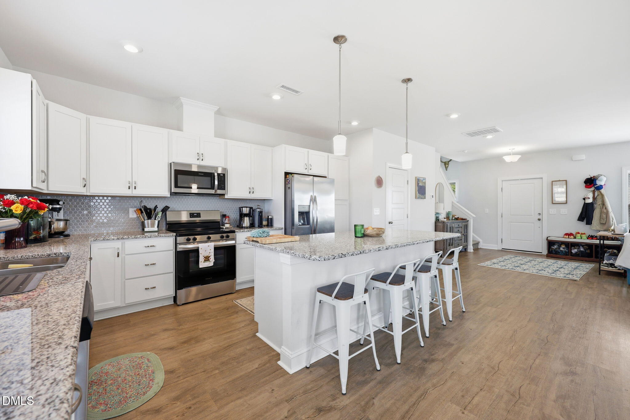 104 Kavanaugh Road Wake Forest, NC 27587 - Photo 13 of 36 a kitchen with stainless steel appliances kitchen island granite countertop a stove a sink a dining table and chairs with wooden floor