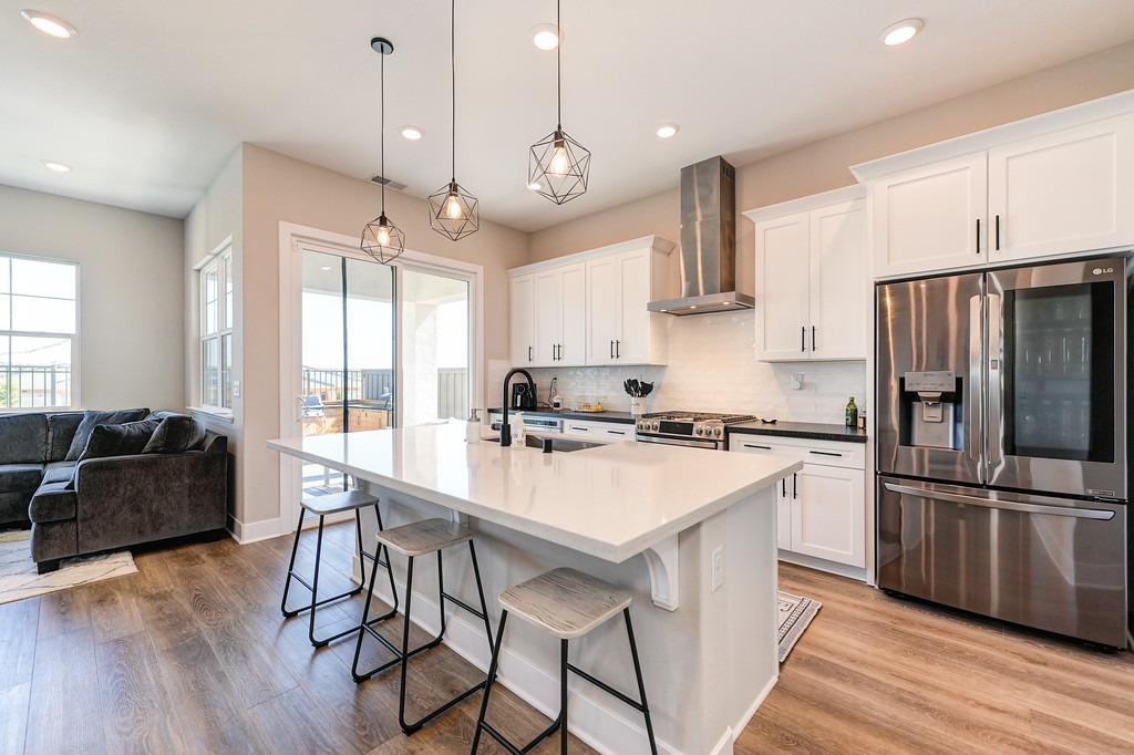 a kitchen with stainless steel appliances granite countertop a stove a refrigerator a sink dishwasher a dining table and chairs with wooden floor
