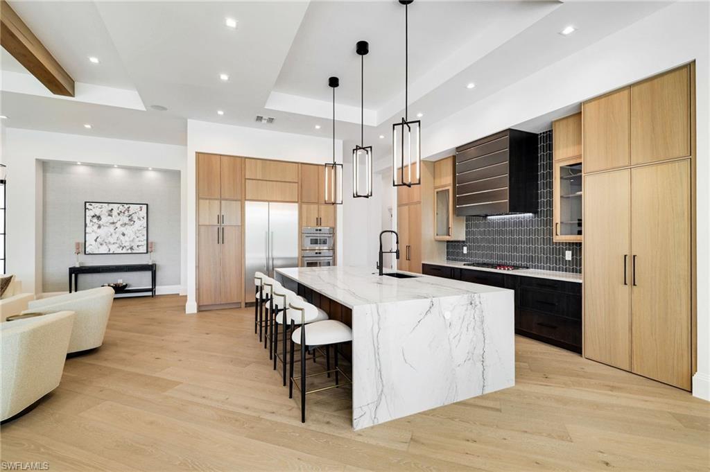 15850 Hampton View Fort Myers, FL 33908 - Photo 11 of 38 Dual tone kitchen with modern cabinets, light wood finished floors, hanging light fixtures, light stone counters, and a kitchen breakfast bar