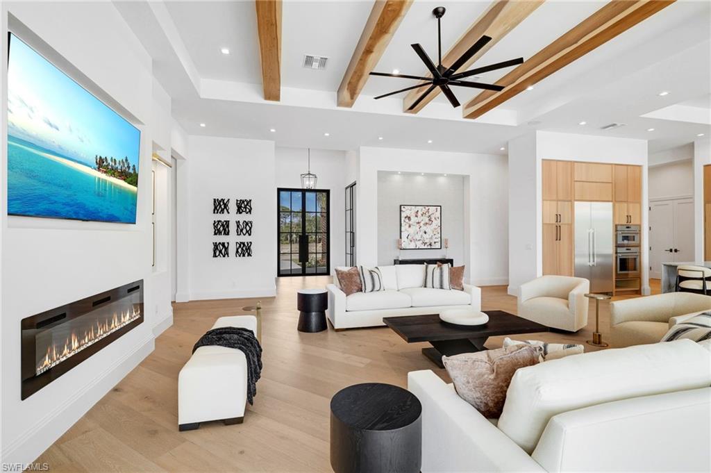 15850 Hampton View Fort Myers, FL 33908 - Photo 13 of 38 Living room with recessed lighting, beam ceiling, a glass covered fireplace, healthy amount of natural light, and light wood-style flooring