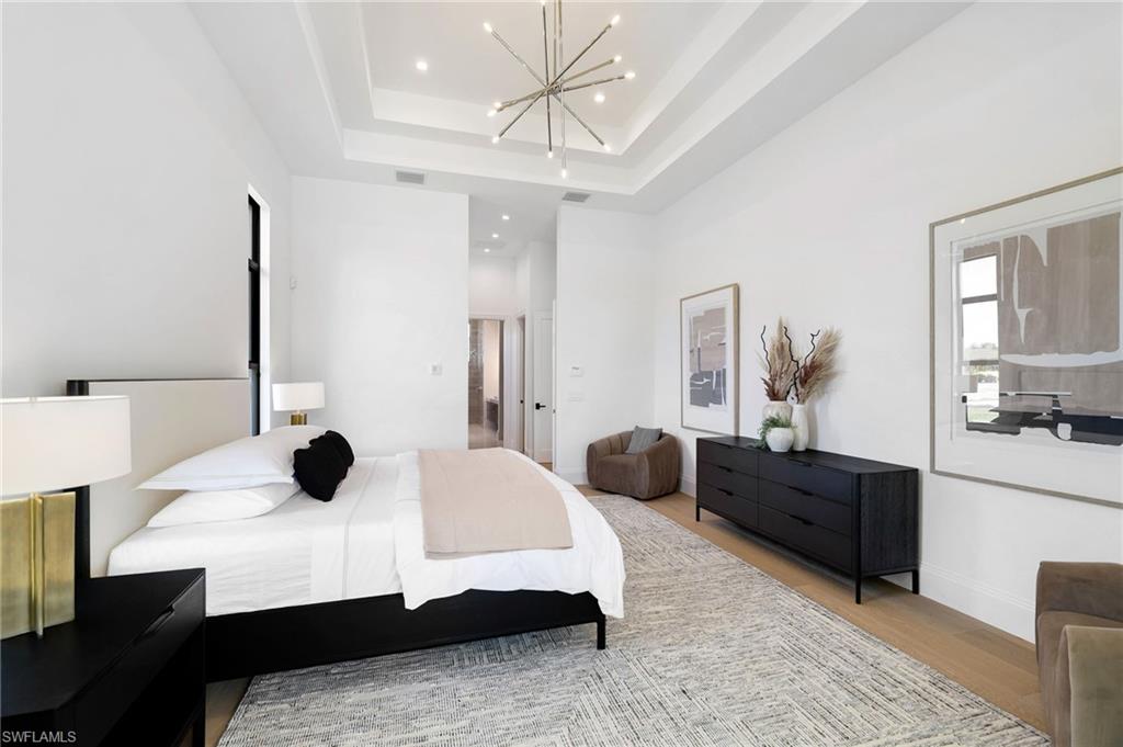 15850 Hampton View Fort Myers, FL 33908 - Photo 15 of 38 Bedroom with access to outside, wood finished floors, suspended lighting, and a tray ceiling