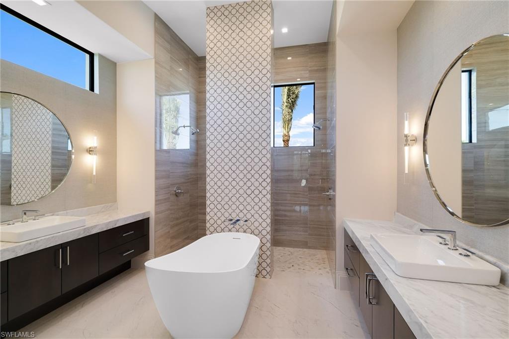 15850 Hampton View Fort Myers, FL 33908 - Photo 17 of 38 Bathroom featuring a walk in shower, two vanities, a freestanding bath, and plenty of natural light
