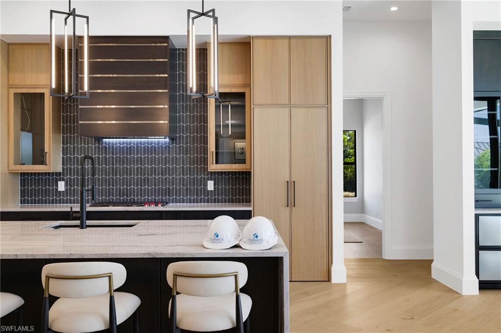15850 Hampton View Fort Myers, FL 33908 - Photo 4 of 38 Kitchen featuring a breakfast bar area, modern cabinets, light stone counters, light wood-style flooring, and light wood finish cabinetry