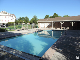 8198 North Cedar Springs Road, Unit T6 Eagle Mountain, UT 84005 - Photo 13 of 13 Resort-style outdoor swimming pool with a concrete deck, surrounded by a low fence and mature trees