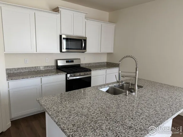 a kitchen with granite countertop a stove and a microwave