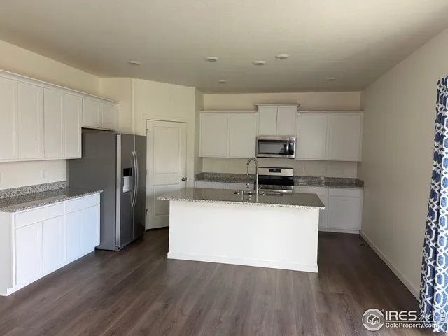 a kitchen with granite countertop a refrigerator stove top oven and sink