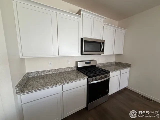 a kitchen with granite countertop white cabinets and black appliances