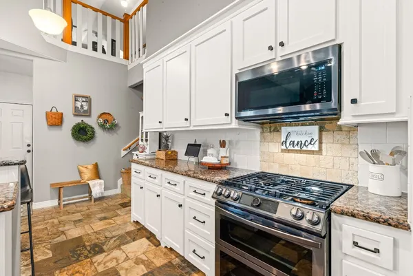 a kitchen with stainless steel appliances granite countertop a stove and a microwave