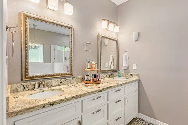 a bathroom with a granite countertop double vanity sink and a mirror