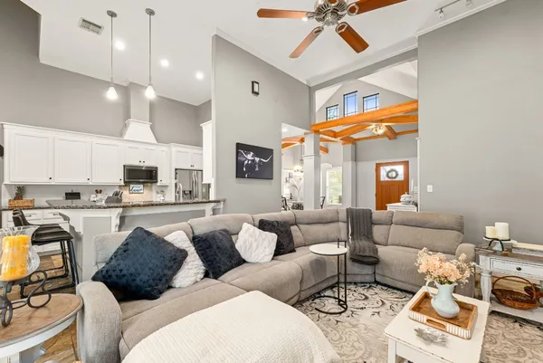 a living room with furniture kitchen view and a chandelier