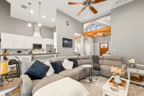 a living room with furniture kitchen view and a chandelier
