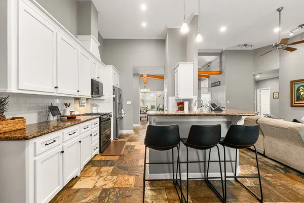 a kitchen with stainless steel appliances granite countertop a sink a stove a refrigerator and white cabinets with wooden floor