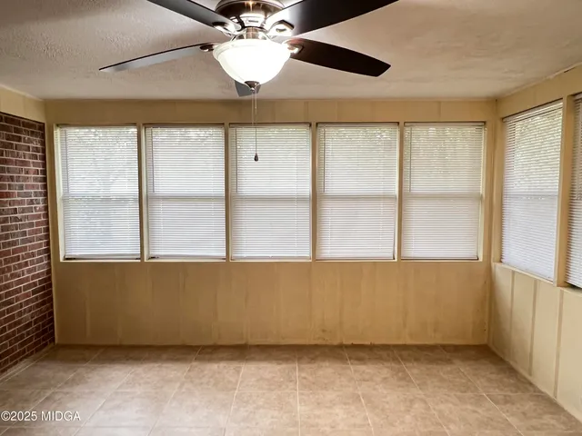 an empty room with a chandelier fan and windows