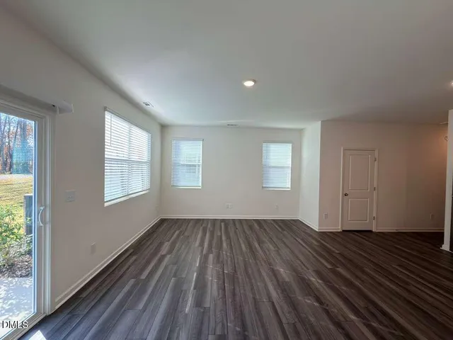 a view of an empty room with wooden floor and window